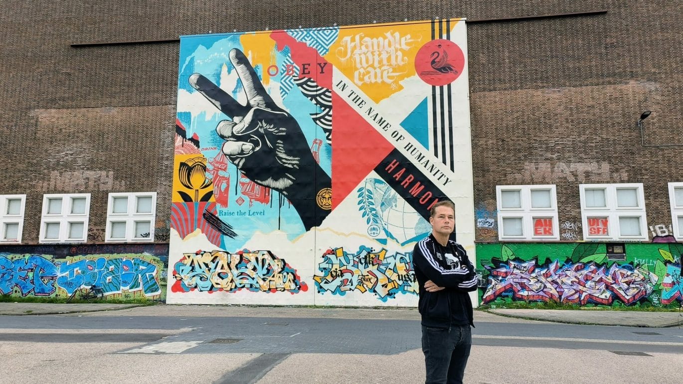 Shepard Fairey poseert voor zijn mural in Amsterdam-Noord